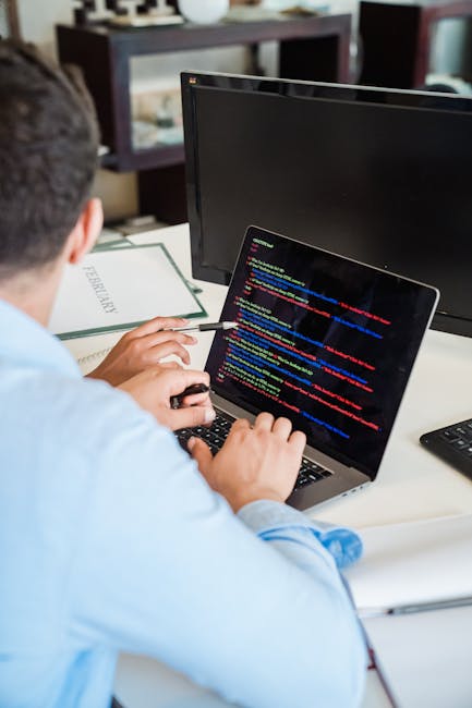 A photograph of a computer screen displaying colorful lines of source code with syntax highlighting, including various programming language elements such as functions, variables, and tags in multiple 